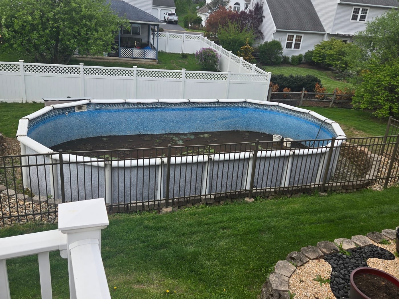 Side angle of above-ground pool with iron railing fence before removal