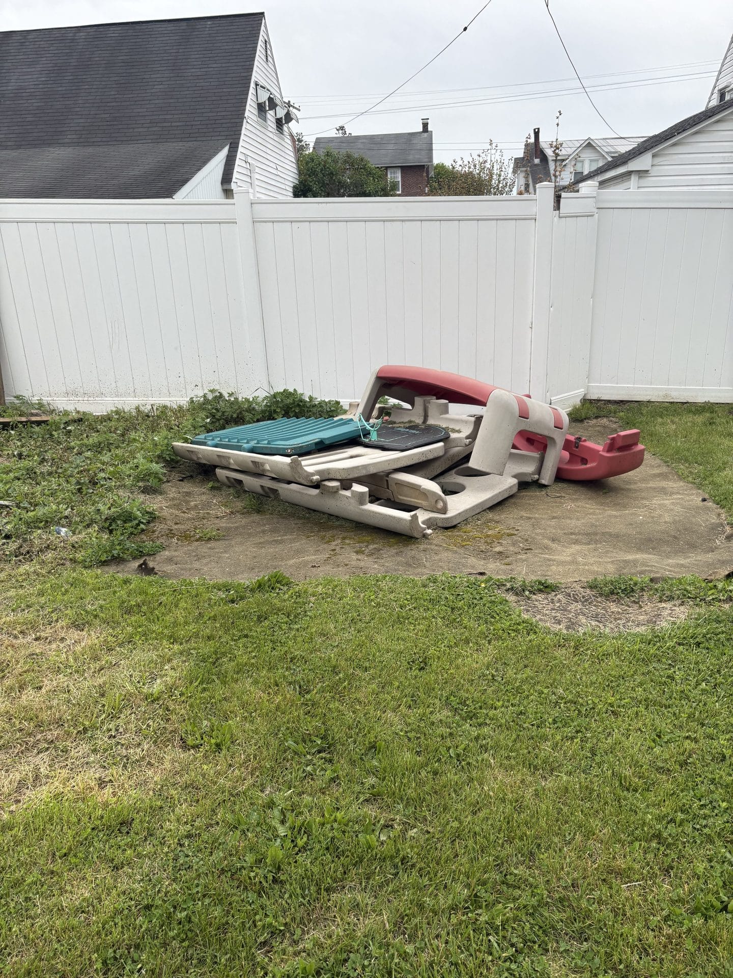 Broken plastic playset sitting on a concrete pad
